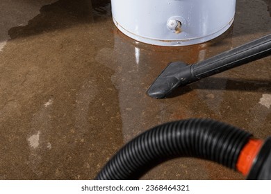 A wet-dry vacuum being used to clean up water from a leaking residential electric water heater.