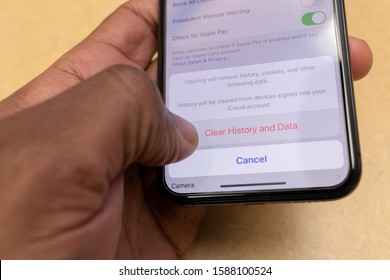 WETHERSFIELD, CONNECTICUT - DECEMBER 12, 2019: African American Man Holding Smart Phone About To Clear Browser History From Apple Safari Mobile Browser