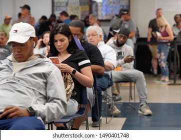 Wethersfield, CT / USA - June 11, 2019: Snapshot of a bored crowd of people in the waiting area (focus on black-haired woman)