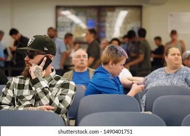 Wethersfield, CT / USA - June 11, 2019: Snapshot Of A Bored Crowd Of People In The Waiting Area (focus On Tattooed Caucasian Man)