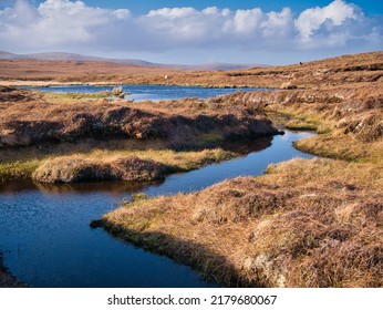 A wetland area forming peat near Eshaness, Northmavine on Mainland, Shetland, UK. Taken on a sunny day with blue sky and white clouds. - Shutterstock ID 2179680067