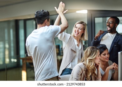 Weve done it again. Shot of a group of colleagues giving each other a high five while using a computer together at work.
