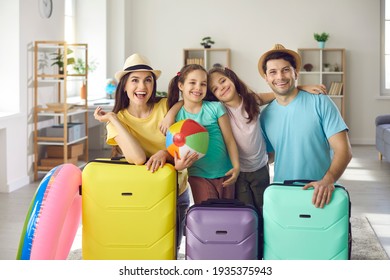 We've packed suitcases and are ready for holiday. Happy young parents and little kids having fun at home before summer vacation trip. Portrait of smiling family with colorful cases looking at camera - Powered by Shutterstock