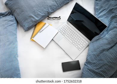 WFH - Work from Home Laptop, Notepad and Mobile Phone on Bed