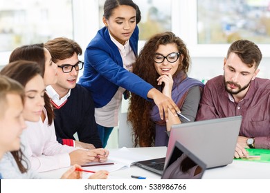 What is that? Beautiful African woman pointing at something out on the laptop to her colleagues diverse creative team of young businesspeople in a meeting working on the computer together teamwork  - Shutterstock ID 538986766