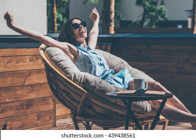 What A Beautiful Day! Beautiful Young Woman Relaxing In A Big Comfortable Chair On Her Outdoor House Terrace