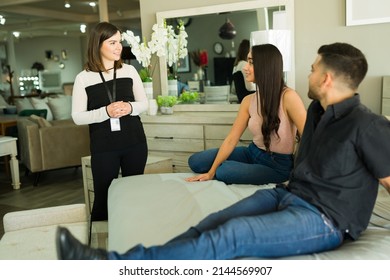 What Can I Help You With? Female Sales Representative Speaking With A Couple Of Clients Looking To Buy New Furniture Bedroom At The Store