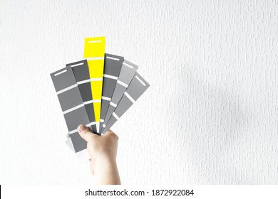 What Color In 2021 Will You Choose? Trendy Pantone Colors On Palette - Illuminating Yellow And Ultimate Gray. Holding Color Swatch Guide In Hand
