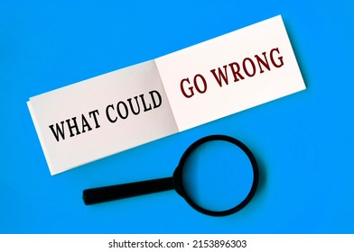 What Could Go Wrong Text On Notepad With Magnifying Glass On Blue Background. Fact Finding Concept
