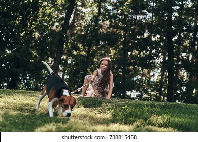 What is there? Cute little girl playing with her dog while crouching outdoors Adlı Stok Fotoğraf