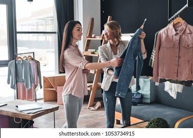 What do you think about this one? Beautiful young woman helping to choose clothes to her customer while working in the fashion boutique