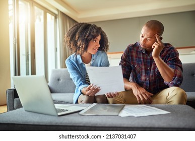 What do you think of this idea. Shot of a focused young couple working on a laptop and doing paperwork together while being seated on a couch at home.
