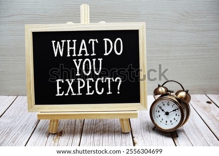 What Do Your Expect? text written on chalkboard with alarm clock on wooden background