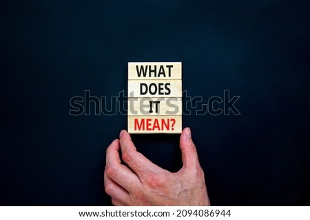 What does it mean symbol. Concept words What does it mean on wooden blocks. Businessman hand. Beautiful black table, black background, copy space. Business and what does it mean concept.