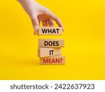 What does it mean symbol. Wooden blocks with words What does it mean. Businessman hand. Beautiful yellow background. Business and What does it mean concept. Copy space.