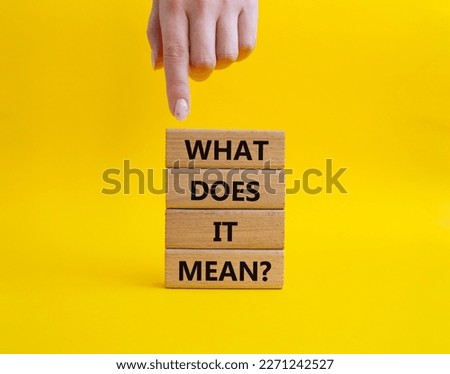 What does it mean symbol. Wooden blocks with words What does it mean. Beautiful yellow background. Businessman hand. Business and What does it mean concept. Copy space.