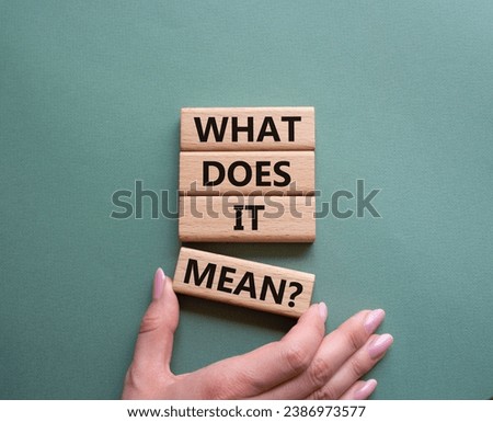 What does it mean symbol. Wooden blocks with words What does it mean. Beautiful grey green background. Businessman hand. Business and What does it mean concept. Copy space.