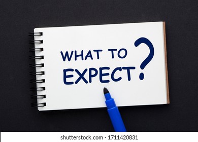 What To Expect Text On Notepad With Blue Marker On Black Background. 