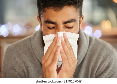 What Am I Going To Do About This Flu. Shot Of A Young Man Blowing His Nose.