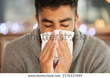 What am I going to do about this flu. Shot of a young man blowing his nose.