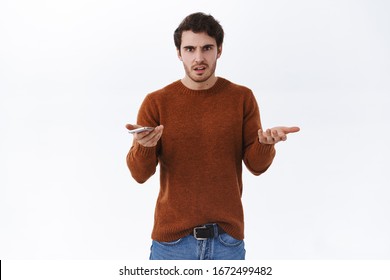 What happening. Pissed-off and confused young man using mobile phone and shrugging bothered, cant understand what happened, had argument, have bad service, hold smartphone and complain