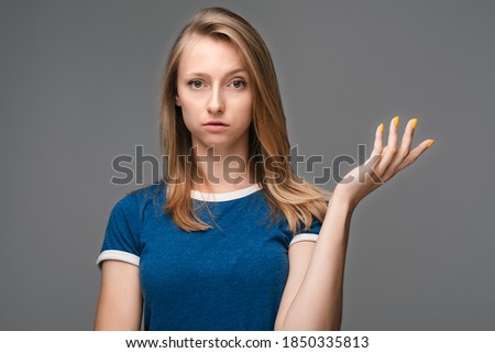 What the hell are you talking about, nonsense. Studio shot of frustrated female with blonde straight hair gesturing with raised palm, frowning, being displeased and confused with dumb question