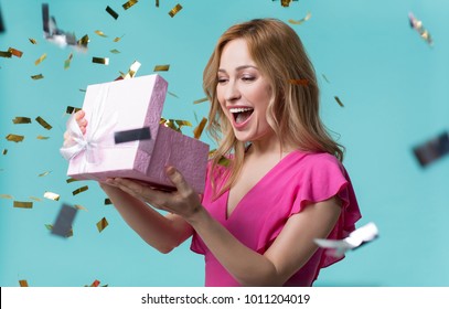 What is inside. Curious young woman is looking into present box and laughing with happiness. Holiday celebration concept - Shutterstock ID 1011204019