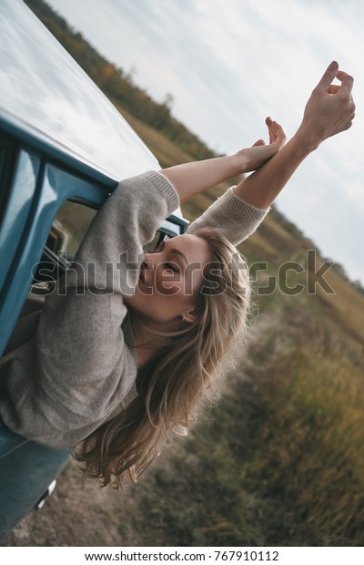 What is life without adventures?\
Attractive young smiling woman leaning out the van?s window and\
keeping arms outstretched while enjoying the car\
travel