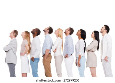 What is that? Side view of positive diverse group of people in smart casual wear looking up while standing in a row and against white background