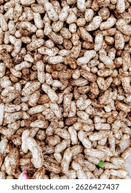 What is visible here are peanuts spread out on the trader's stall at the market, The merchandise is spread out in the open while drying in the sun so that it doesn't rot.