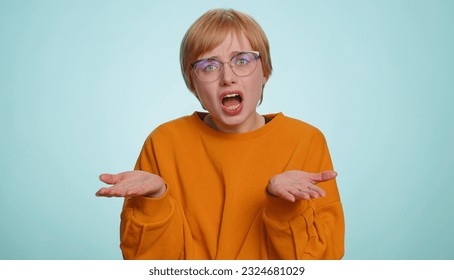 What Why. Sincere irritated woman in glasses raising hands in indignant expression, ask reason of failure demonstrating disbelief irritation by trouble. Pretty confused blonde girl on blue background