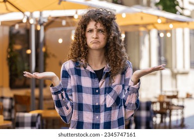 What. Why. Surprised frustrated pretty young woman raising hands asking reason of failure, demonstrating disbelief irritation by troubles outdoors. Confused girl walking in urban city sunshine street