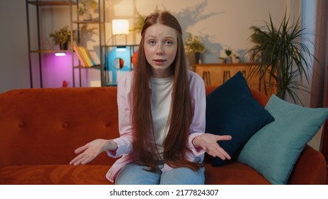 What. Why. Young Teen Child Girl Raising Hands In Indignant Expression, Asking Reason Of Failure, Demonstrating Disbelief Irritation By Troubles At Home Apartment. Children Kid In Room Sitting On Sofa