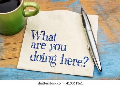 -What are you doing here? Handwriting on a napkin with cup of coffee against gray slate stone background