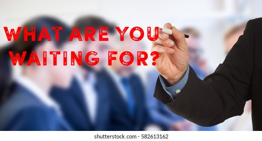 What Are you Waiting for? Male hand in business wear holding a thick pen, writing on an imaginary screen at the camera, business team in background, digital composing.