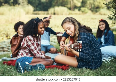 What's summer camp without a singalong. Shot of a group of teenagers playing musical instruments in nature at summer camp. - Powered by Shutterstock