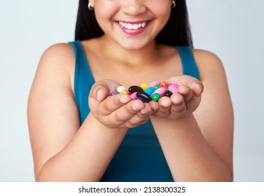 Whats your favorite flavor. Studio shot of a cute young girl holding a handful of colorful jelly beans. - Powered by Shutterstock