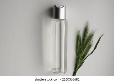 Wheat barley rye oat essence in a glass bottle and green young fresh wheat ears on white background with copy space. Cosmetic essence oil template ad. Bottle product with wheat rye barley