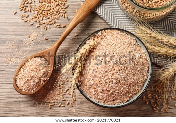 Wheat bran, kernels and spikelets on wooden table,\
flat lay