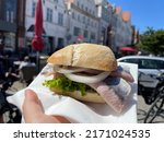 Wheat bun with traditional north german marinated fish matjes filet with onion rings, tasty street food snack in female hand close up in Husum, Germany