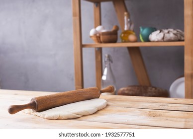Wheat dough at flour powder and rolling pin on table for homemade bread cooking or baking. Food set at wooden tabletop near wall background texture. Bakery concept