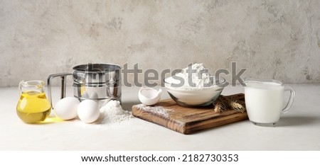 Wheat flour with eggs, oil and milk on table