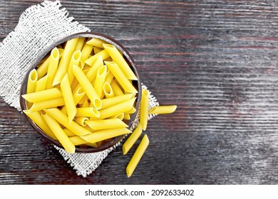 Wheat flour penne pasta in a bowl of coconut shells on sacking on a wooden board background from above - Powered by Shutterstock