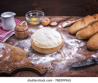 wheat yeast dough for bread and rolls in a wooden bowl on a table in the middle of the ingredients, top view - Shutterstock ID 788399965