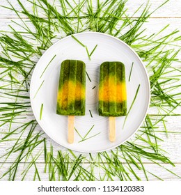 Wheatgrass And Orange Popsicles On A White Plate