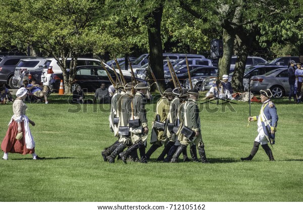 WHEATON, ILLINOIS/USA - SEPTEMBER 9, 2017:\
An officer with drawn saber leads infantry ahead of a woman during\
a tactical demonstration at a reenactment of the American\
Revolutionary War\
(1775-1783).