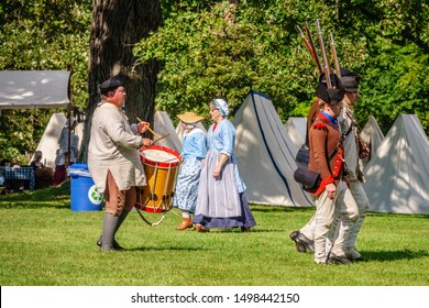 WHEATON, IL/USA - SEPT. 7, 2019: Drummer Follows Marching Militiamen While Two Women In Period Dress Walk In The Opposite Direction At A Reenactment Of The American Revolutionary War (1775-1783).