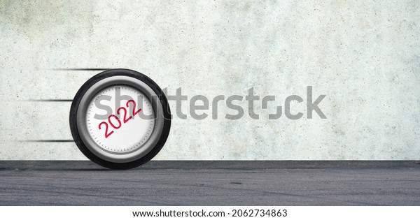 Wheel of a 2022 car is rolling down the road.\
The concept of the coming New Year 2022. New year concept. Copy\
space. Background.