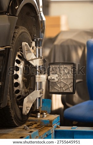 Wheel alignment sensor mounted on car wheel in auto service workshop. Vehicle diagnostics and adjustment process. Riga, Latvia – March 16, 2026.