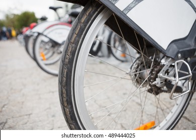 Wheel of bicycle parked at parking lot in the urban street.City transportation for rent.Green power transport.Hit pedals and ride city streets fast and safe - Shutterstock ID 489444025